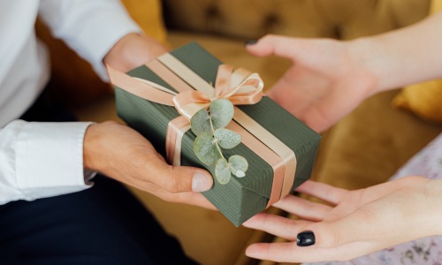 man and woman exchanging a gift wrapped in eucalyptus