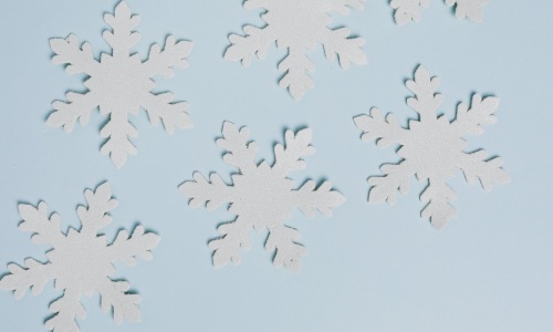 Paper snowflakes sitting on a blue background made from a DIY craft