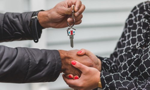 two people holding hands handing over key to new apartment rayzor ranch