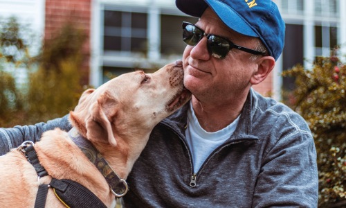 Dog licking mans face as they enjoy pet friendly amenities