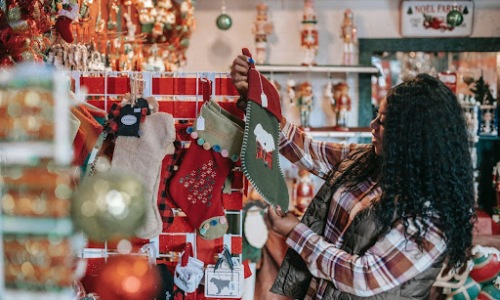 Woman holding up a stocking in front of Christmas decor